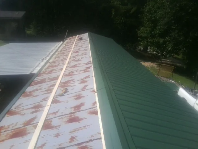 Old rusted panels beside newly installed green metal roofing — Wind Damage Roof Repair by Roofing Brothers in Lewistown