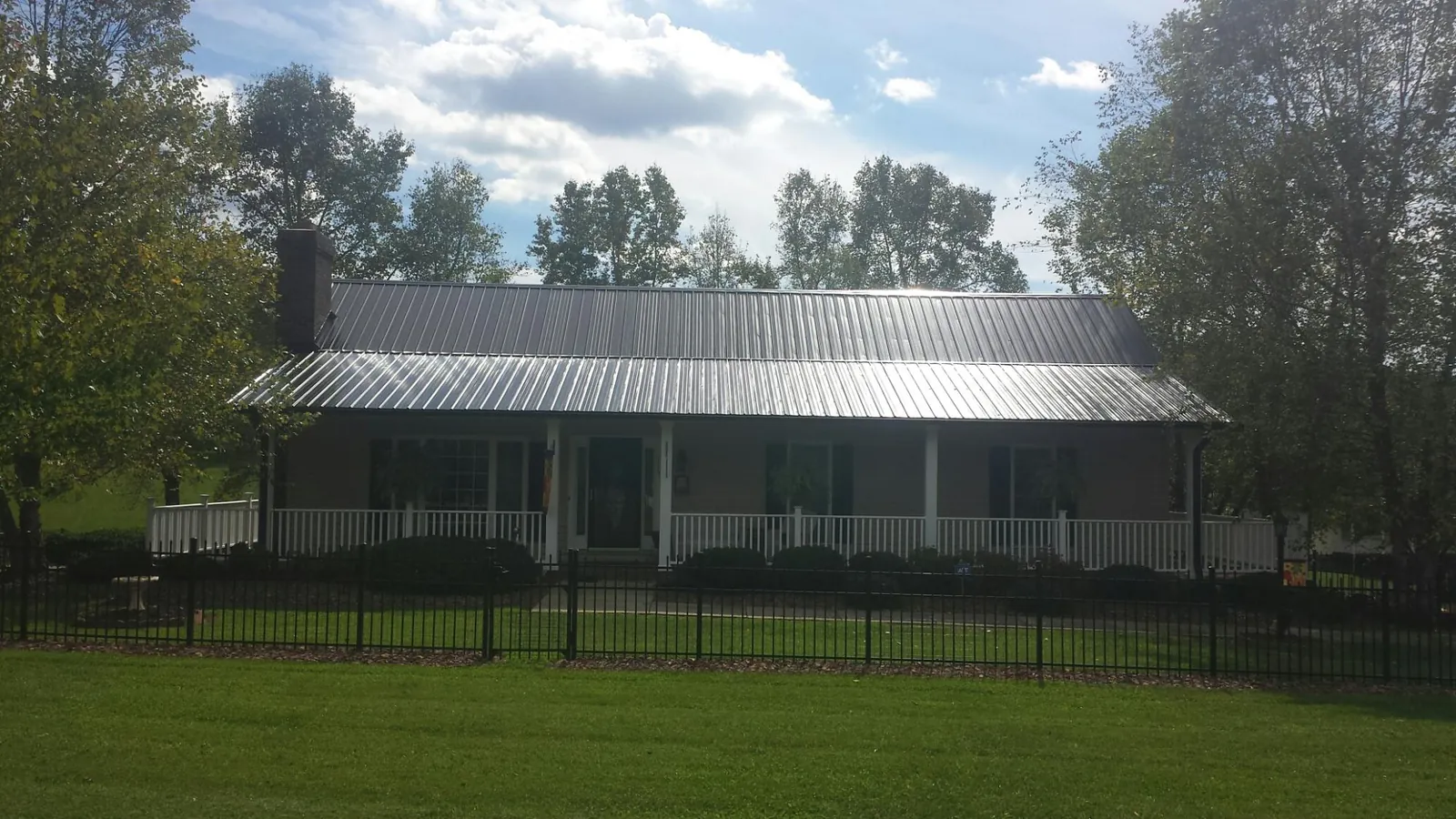 Gray metal roof on a brick ranch with a full width front porch — Gutter Guard Installation work by our crew in Lewistown